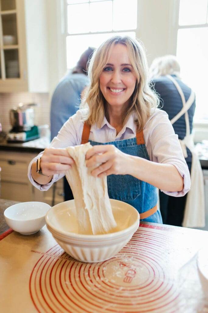 Heather in the kitchen, stretching bread dough out of a bowl.